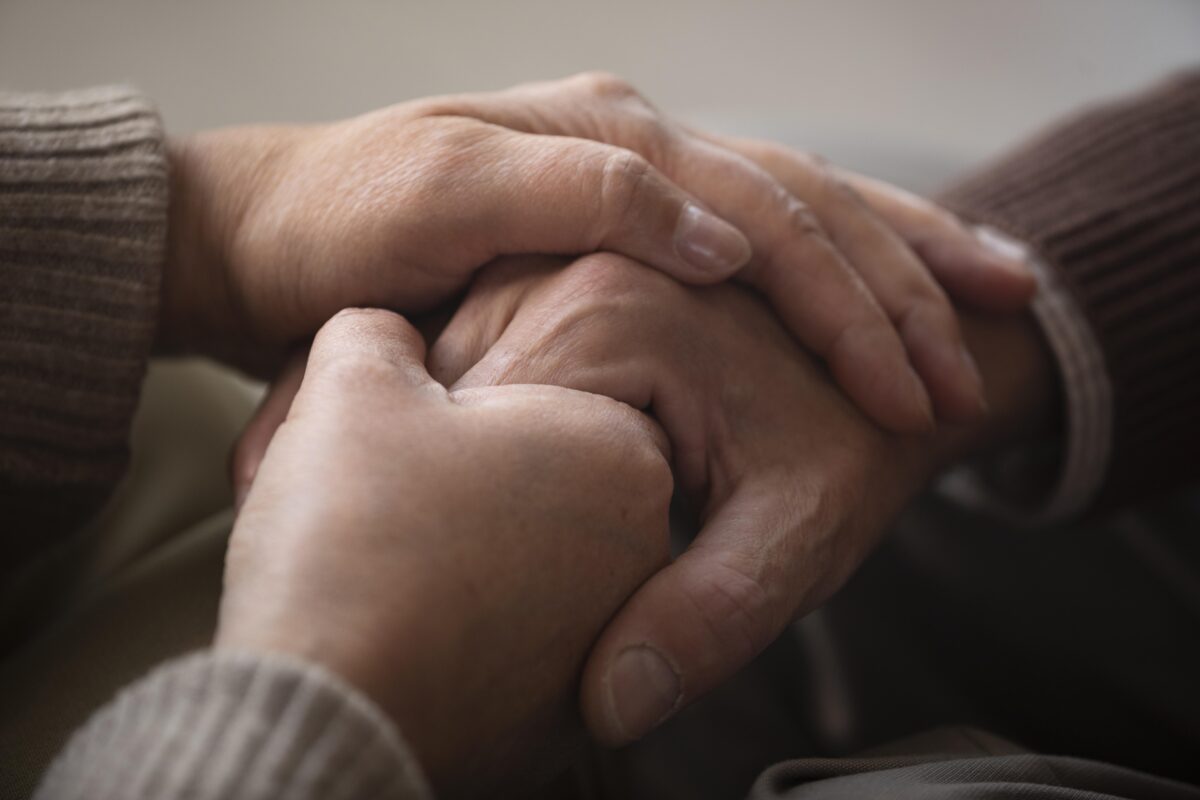 Duas pessoas dando as mãos, com close nas mãos